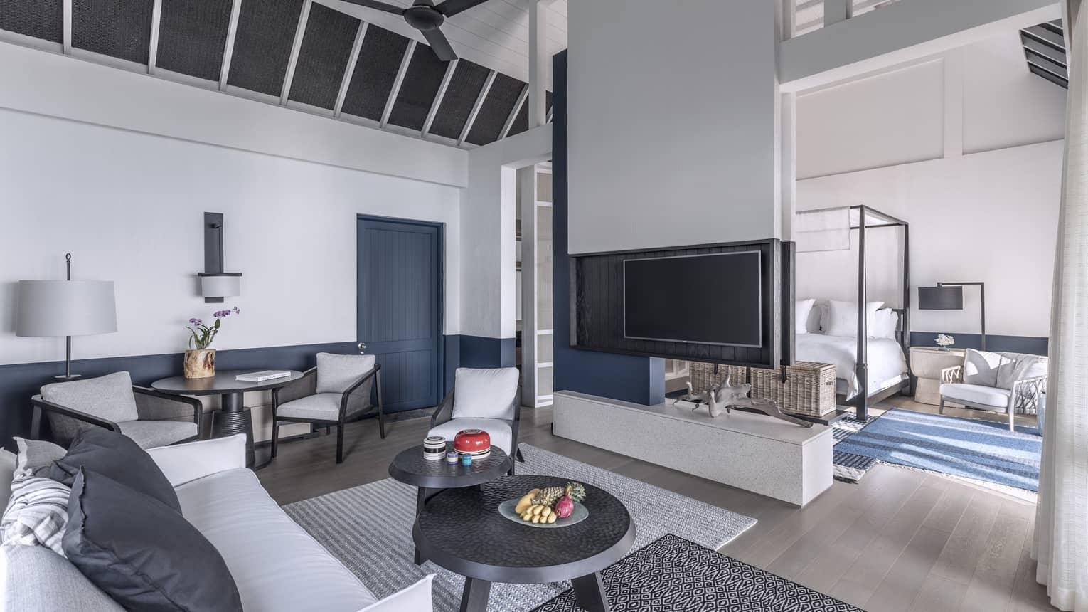A brightly lit, cozy living room with a television, couch and access to the bedroom