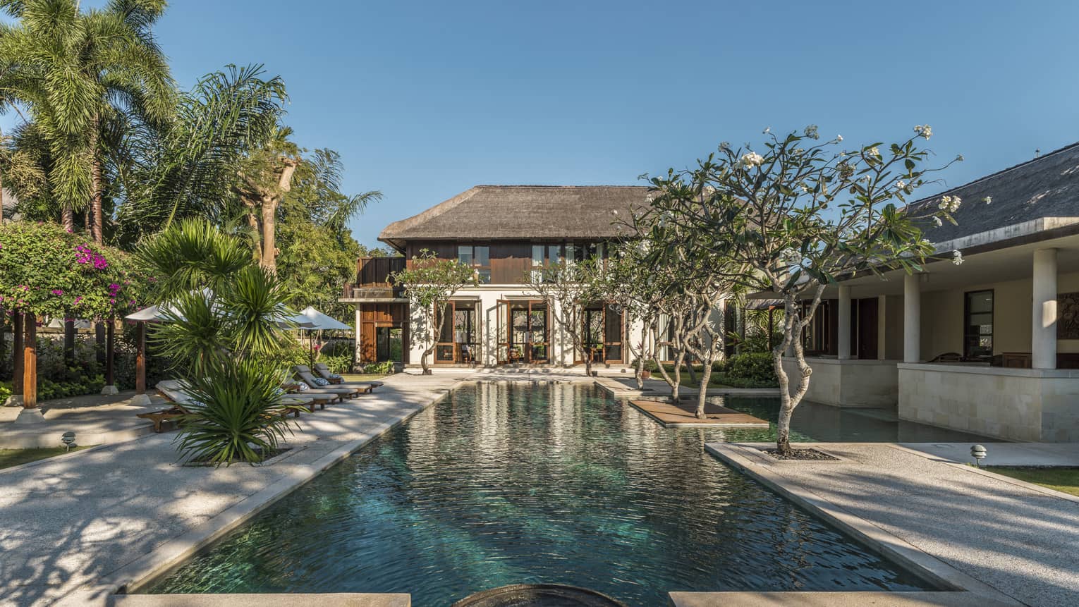 Turquoise water in long outdoor swimming pool leading to Residence 