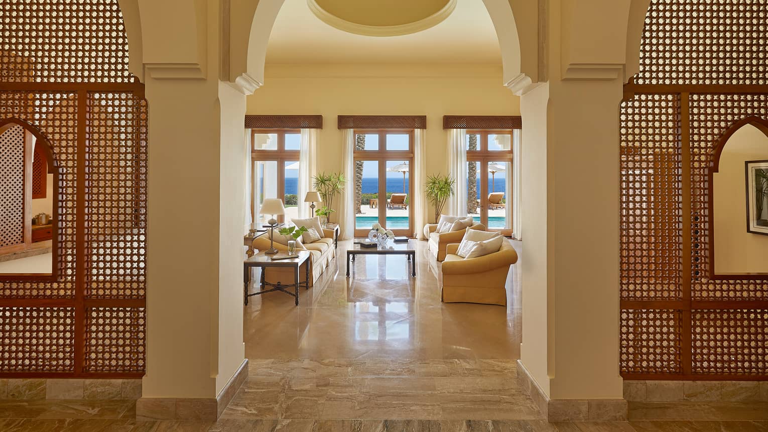 Royal Suite sunny living room under soaring ceiling past decorative wood screens