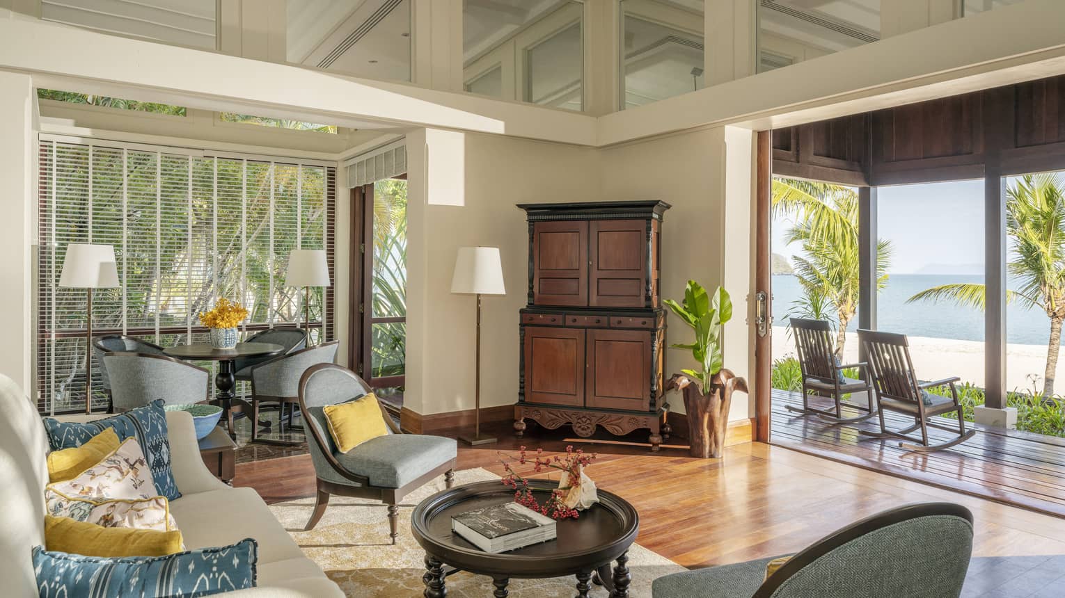 Living room with teak floors and opening to covered terrace looking out to beach