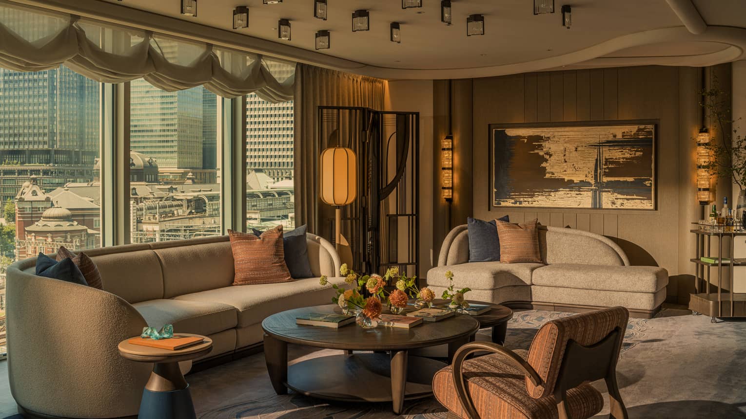 Luxury hotel suite living room with city views, two sofas, large coffee table and arm chair