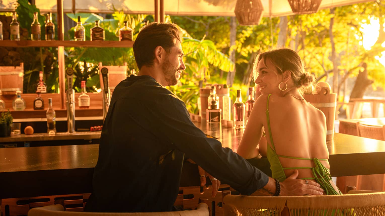 Couple sits at a bar drenched in natural sunlight
