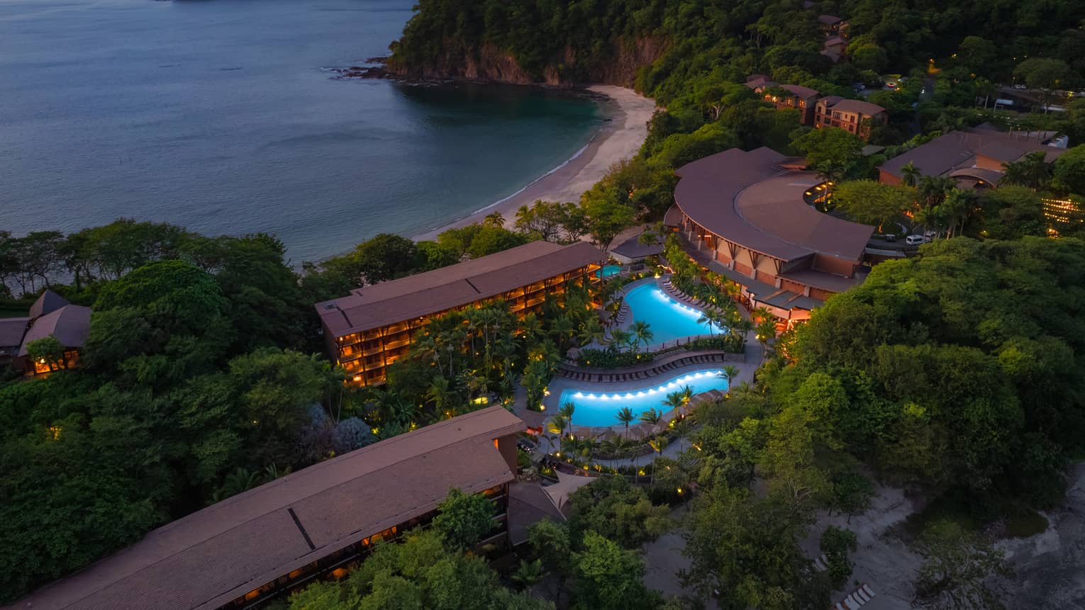 Aerial view of beachside resort and two outdoor pools at night