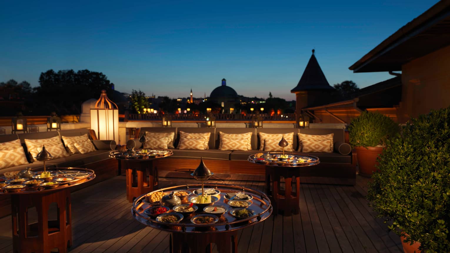 Large brass tables with small appetizer dishes on patio at night