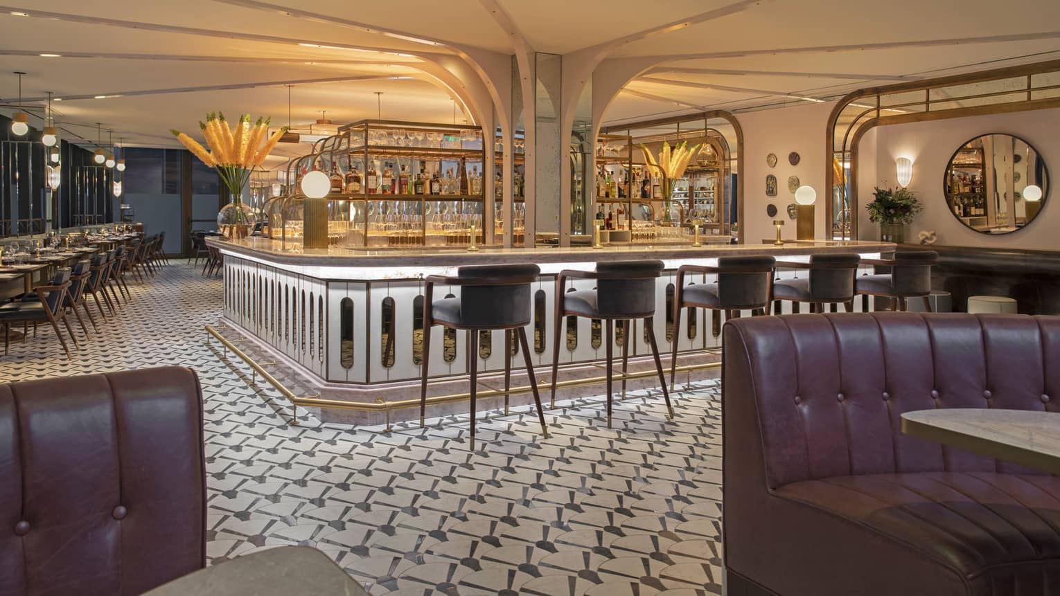 Illuminated bar in a restaurant, with five leather high chairs, tiled floor