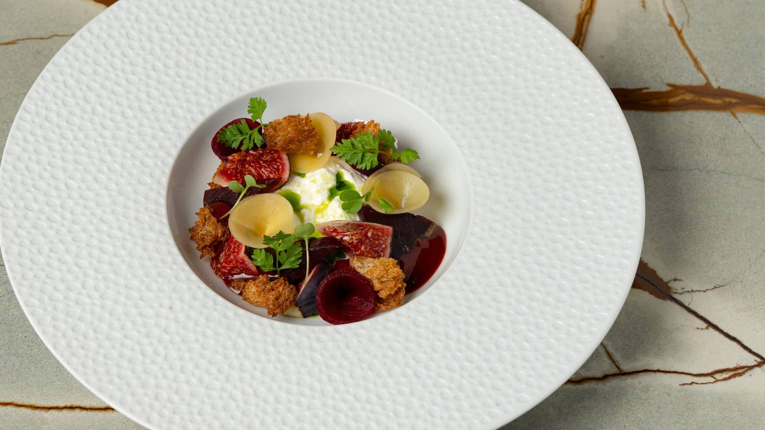 A shallow round bowl with wide textured edge holds colourful food items.