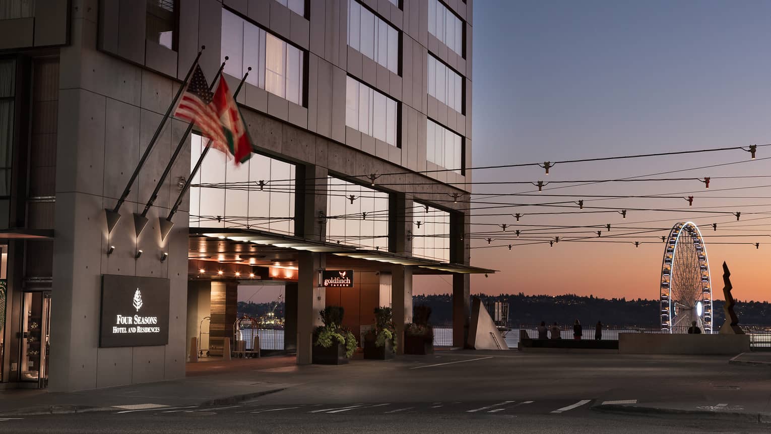 Four Seasons hotel exterior, front entrance with the Seattle Great Wheel in background at sunset