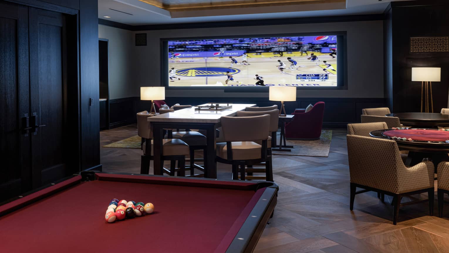 Games room with billiards table, card table and large screen playing a basketball game.