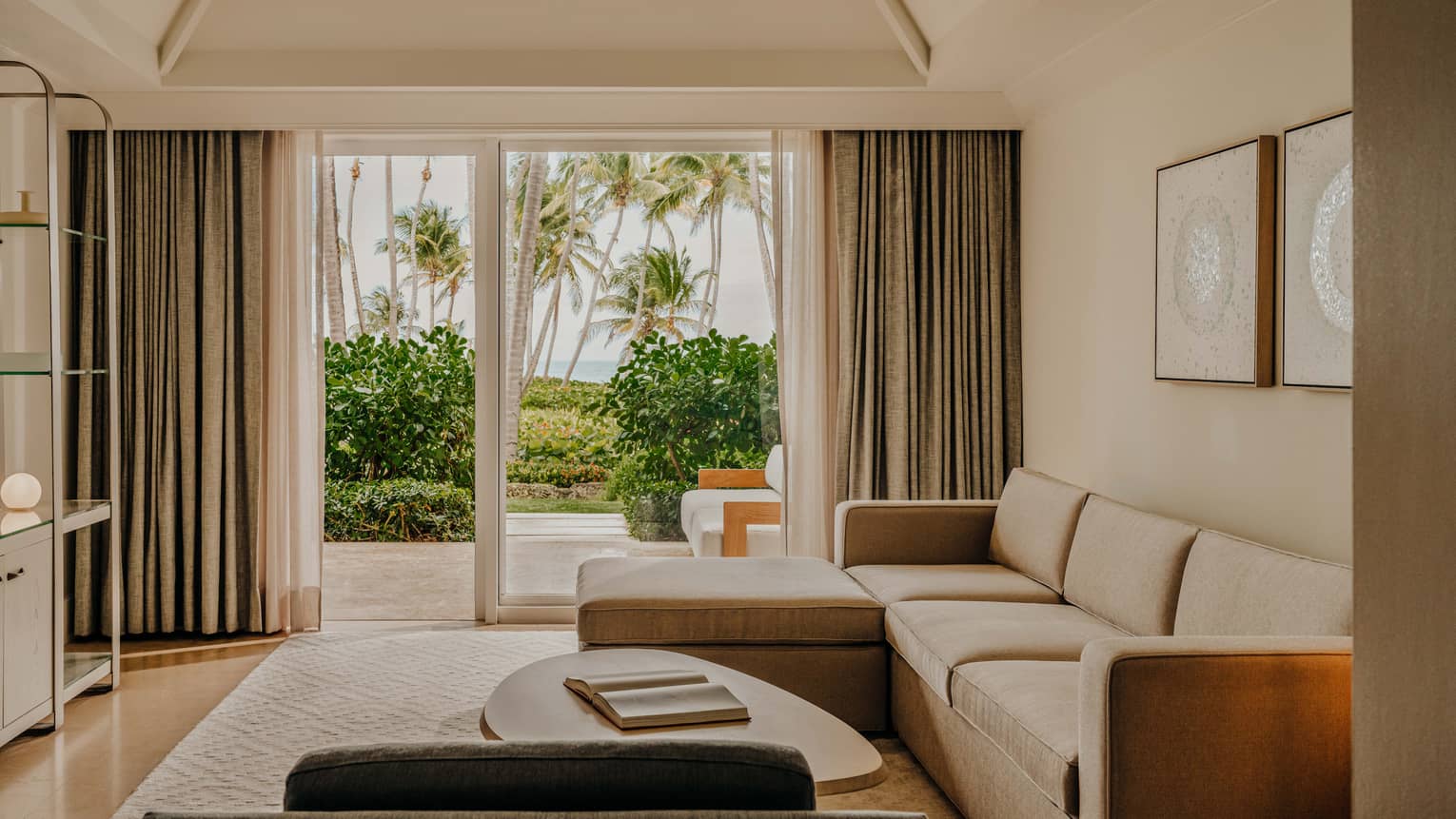 Contemporary living room of a resort suite, featuring a light-brown sofa and walk-out terrace