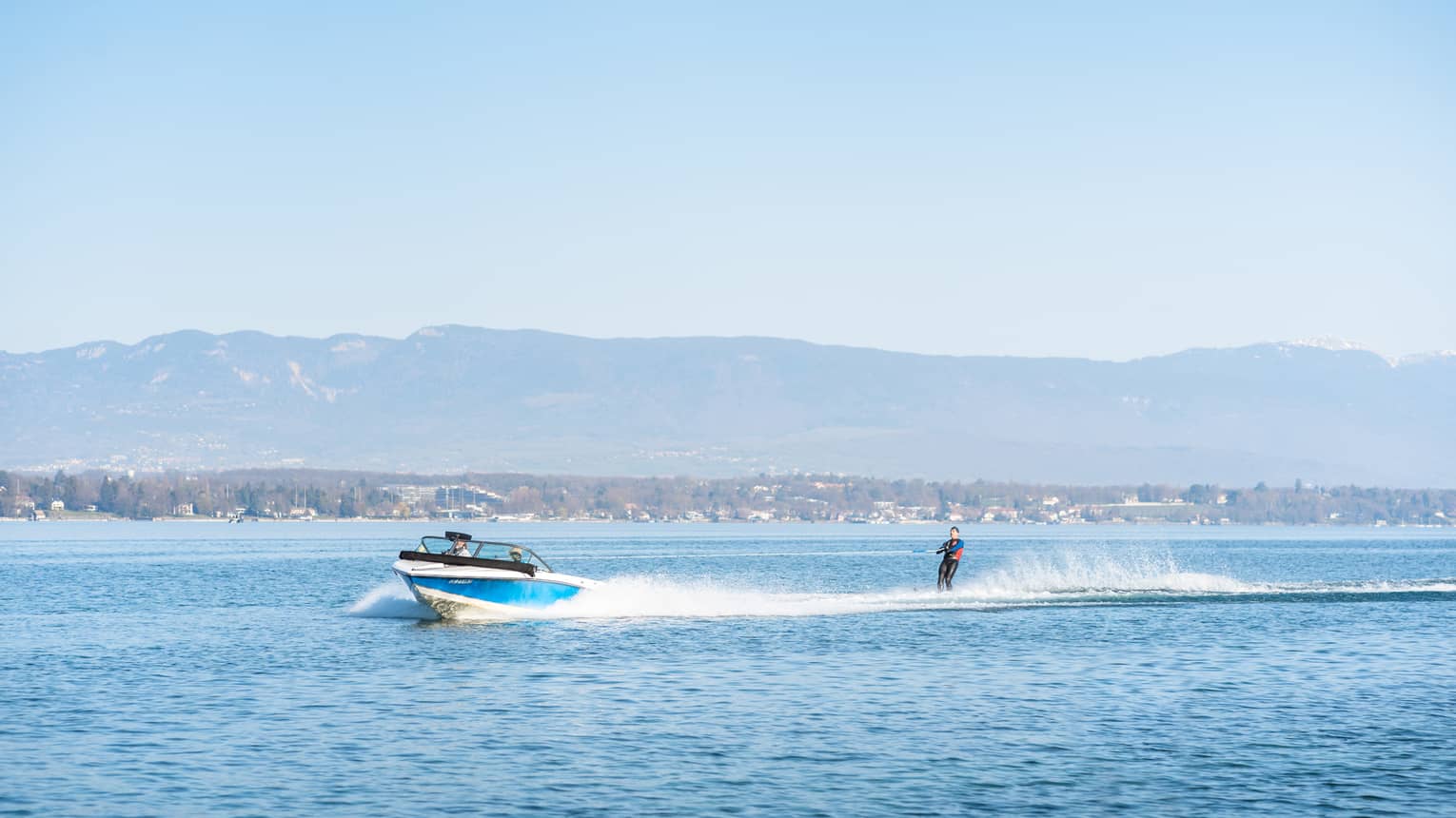 Blue-and-white boat pulling waterskiier on Lake Geneva
