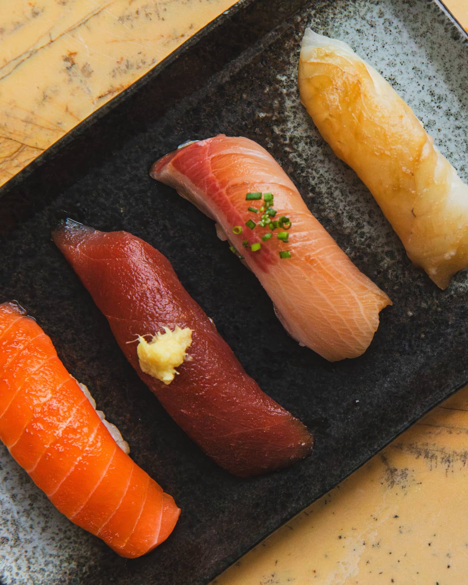 Sashimi on a black tray next to a 17-course menu