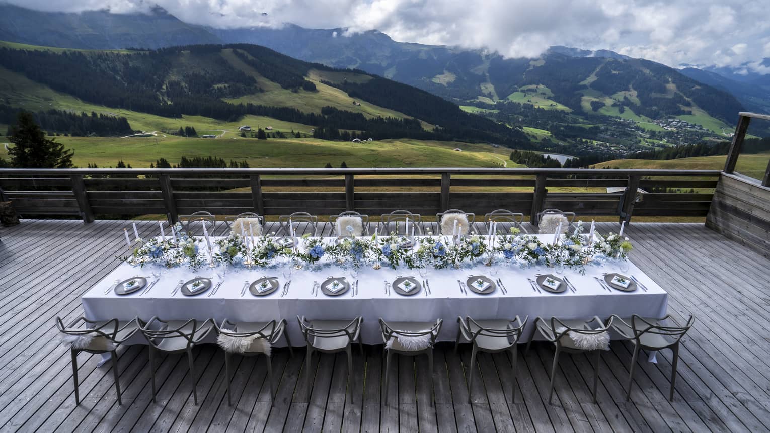 Elegantly set formal banquet table on wooden deck with mountain views