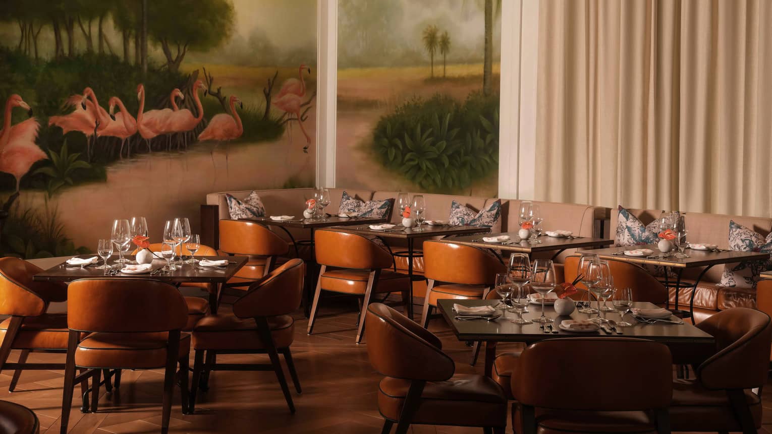 Dining room with brown leather chairs, rectangular tables and a large mural featuring flamingos