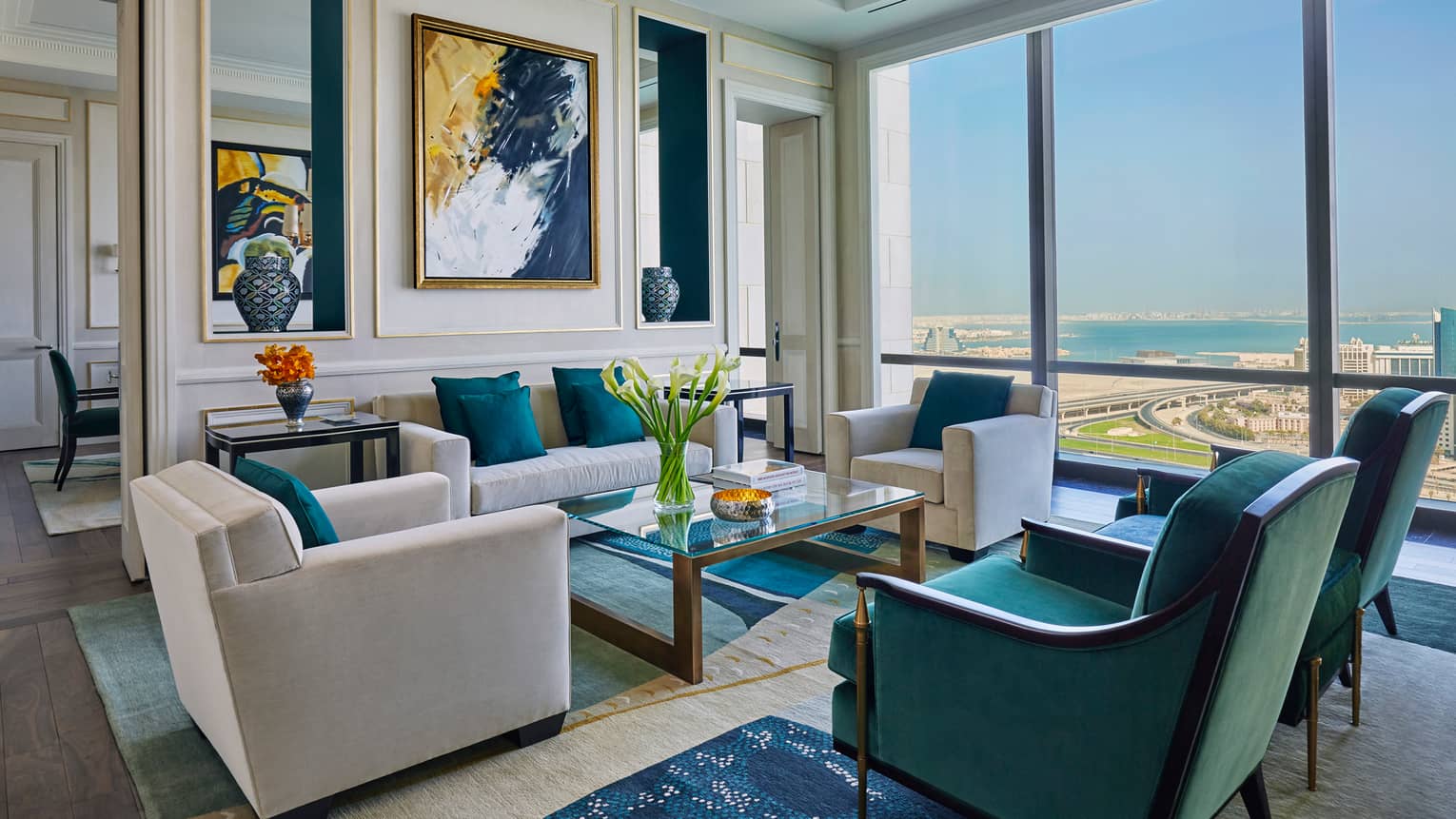Hotel room living area with beige, green and gold seating area, modern art on wall, sunny windows