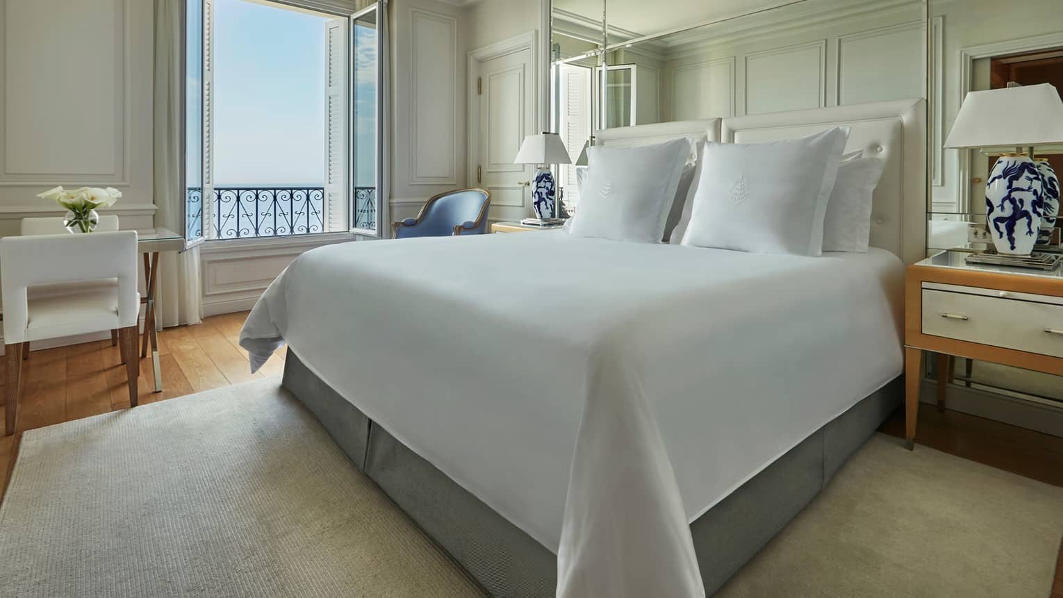 Hotel room, bed with white linens, dining table, open window