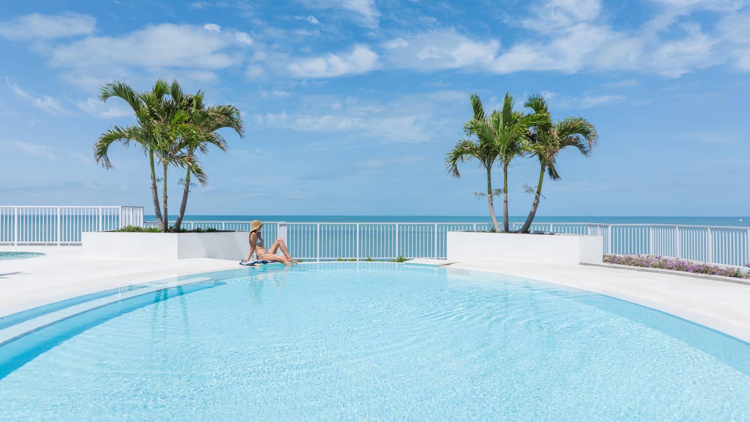 Resort pool in tropical setting, with an ocean view