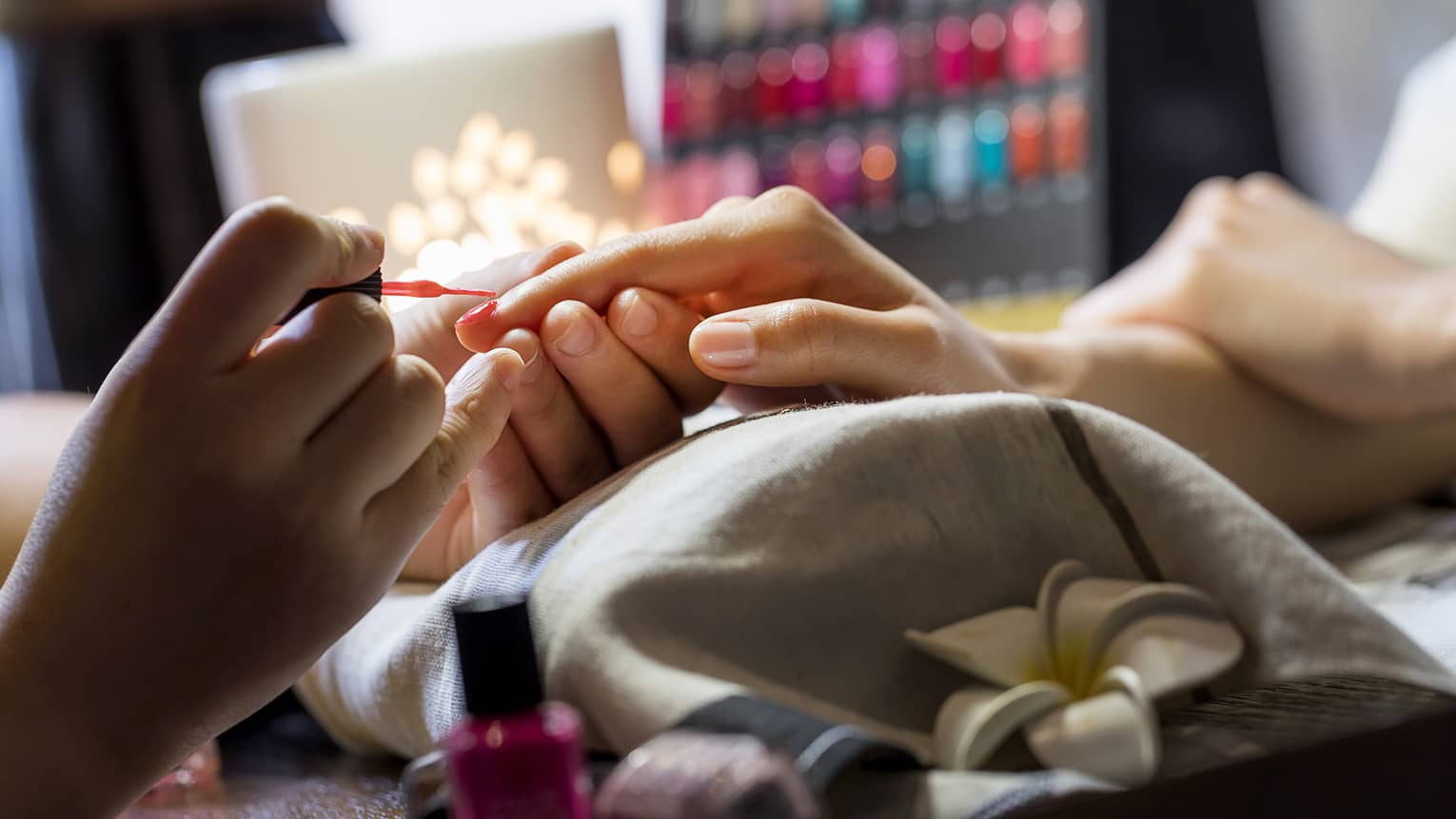 Close-up of manicure, hands resting on pillow as nails painted
