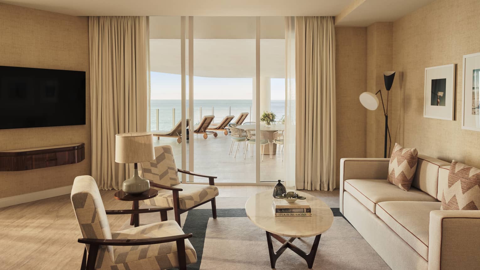 Living room with sofa, two arm chairs, TV, walk-out terrace with ocean view