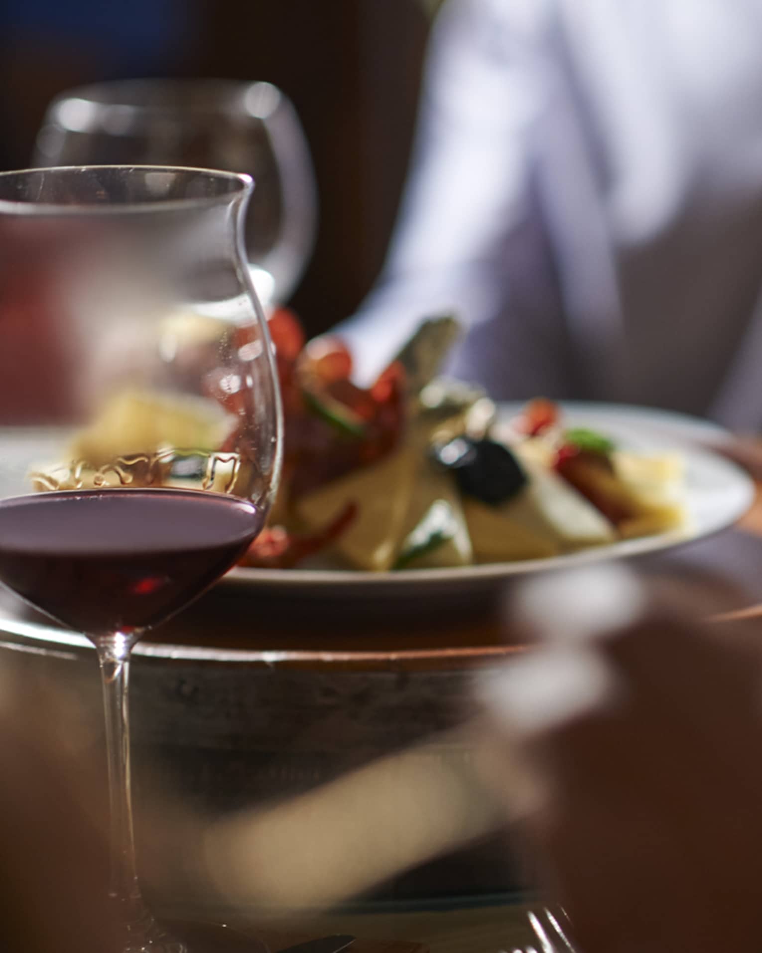 Close-up of man's hand holding a glass of white wine at formal dinner table