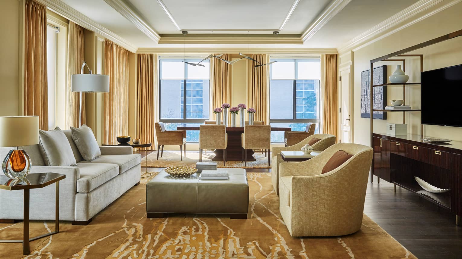 Imperial Suite grey sofa, modern brown armchairs on large area rug, dining table in front of floor-to-ceiling corner windows