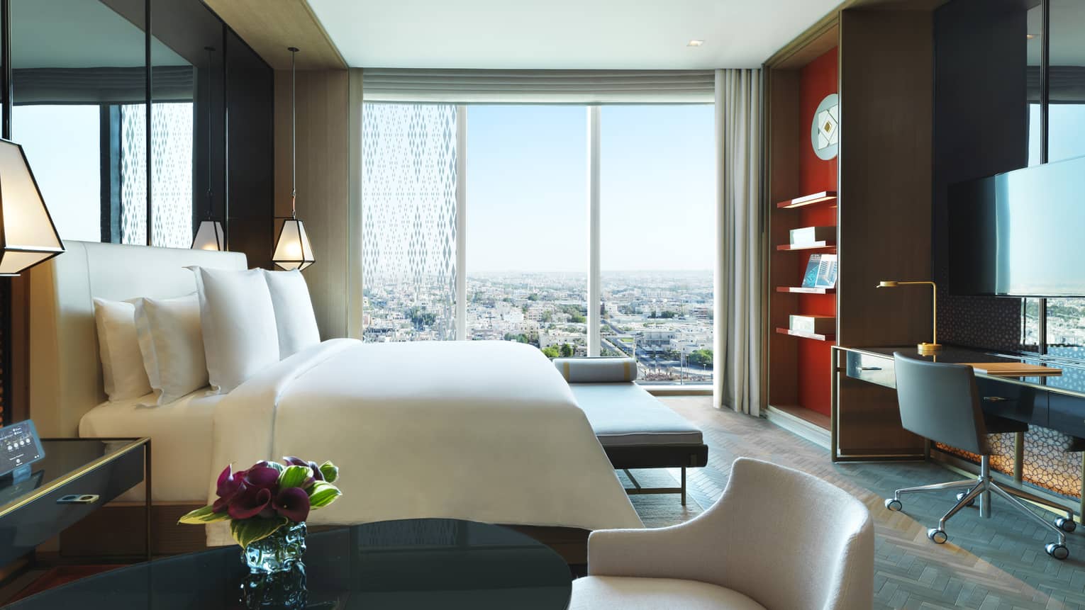 Side view of Premier Room small table and chair, hotel bed with bench at foot, work desk, large window