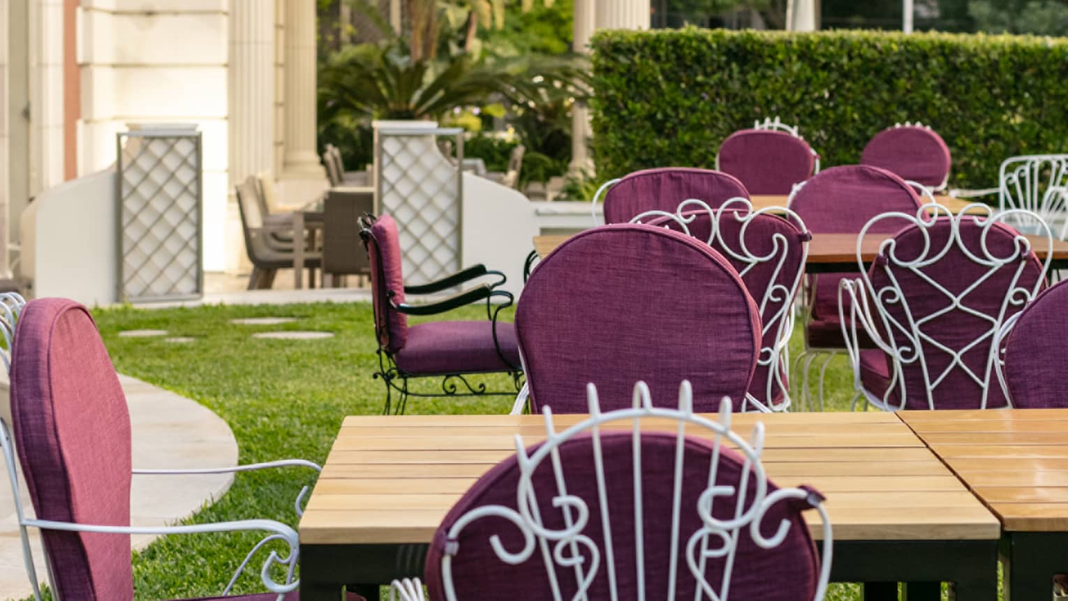 Several tables set up on a terrace with purple chairs. 