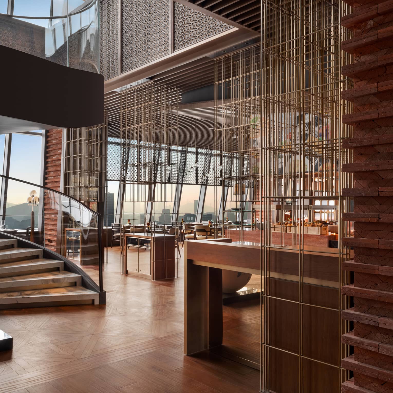 Two large, rounded sculptures set next to a curved staircase in a bright wood-hued restaurant with a wall of large windows.