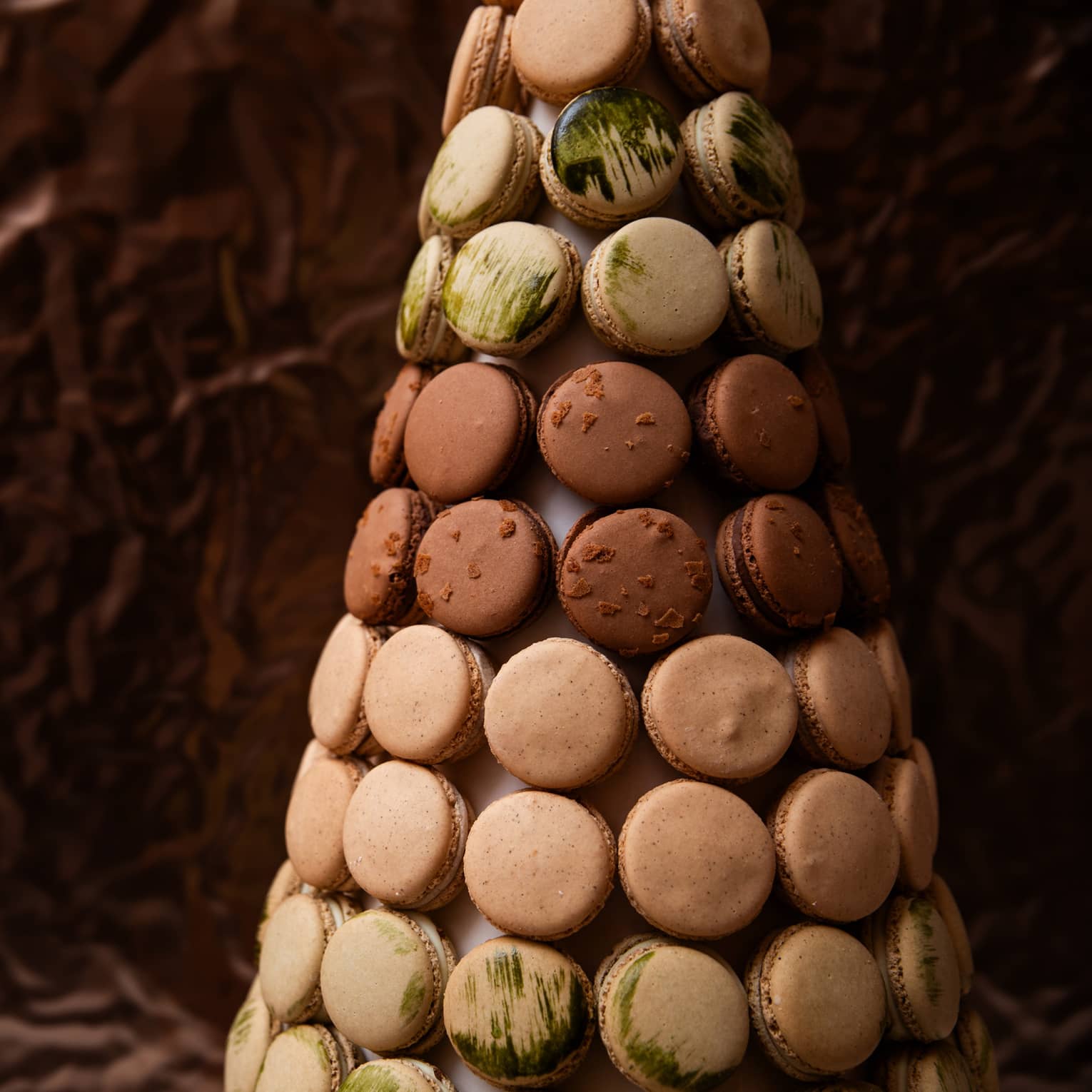 French macrons in shades of brown, beige and light green are artfully displayed in a tree-like shape