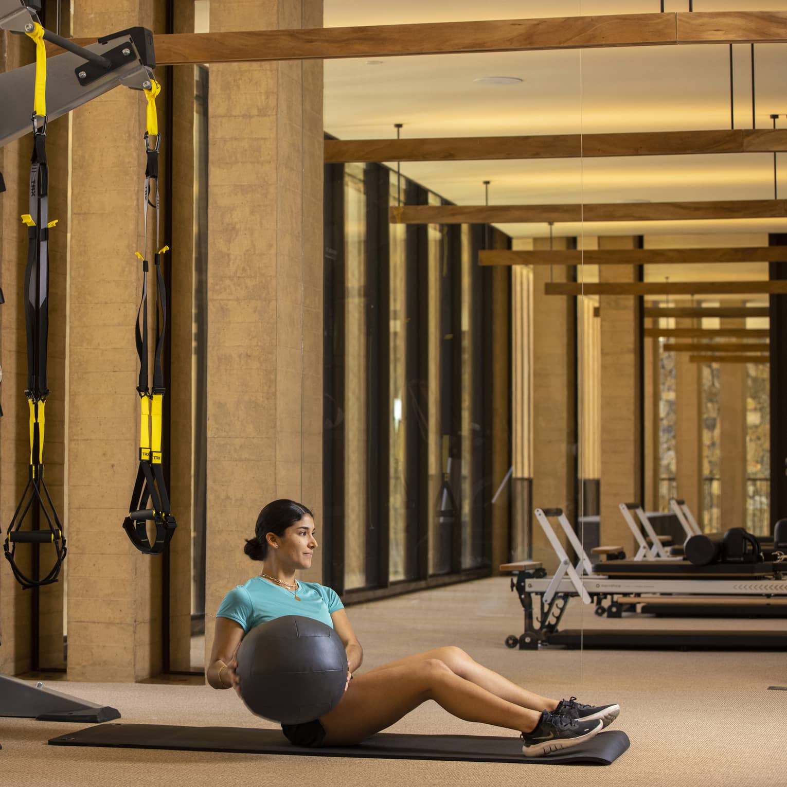 A person exercises with an exercise ball on a mat in an indoor fitness centre space.