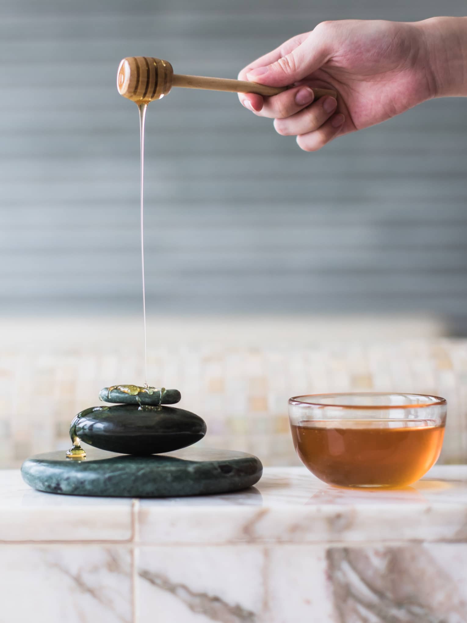 Royal Moroccan Hammam, honey drizzled on stack of black stones next to bowl of honey