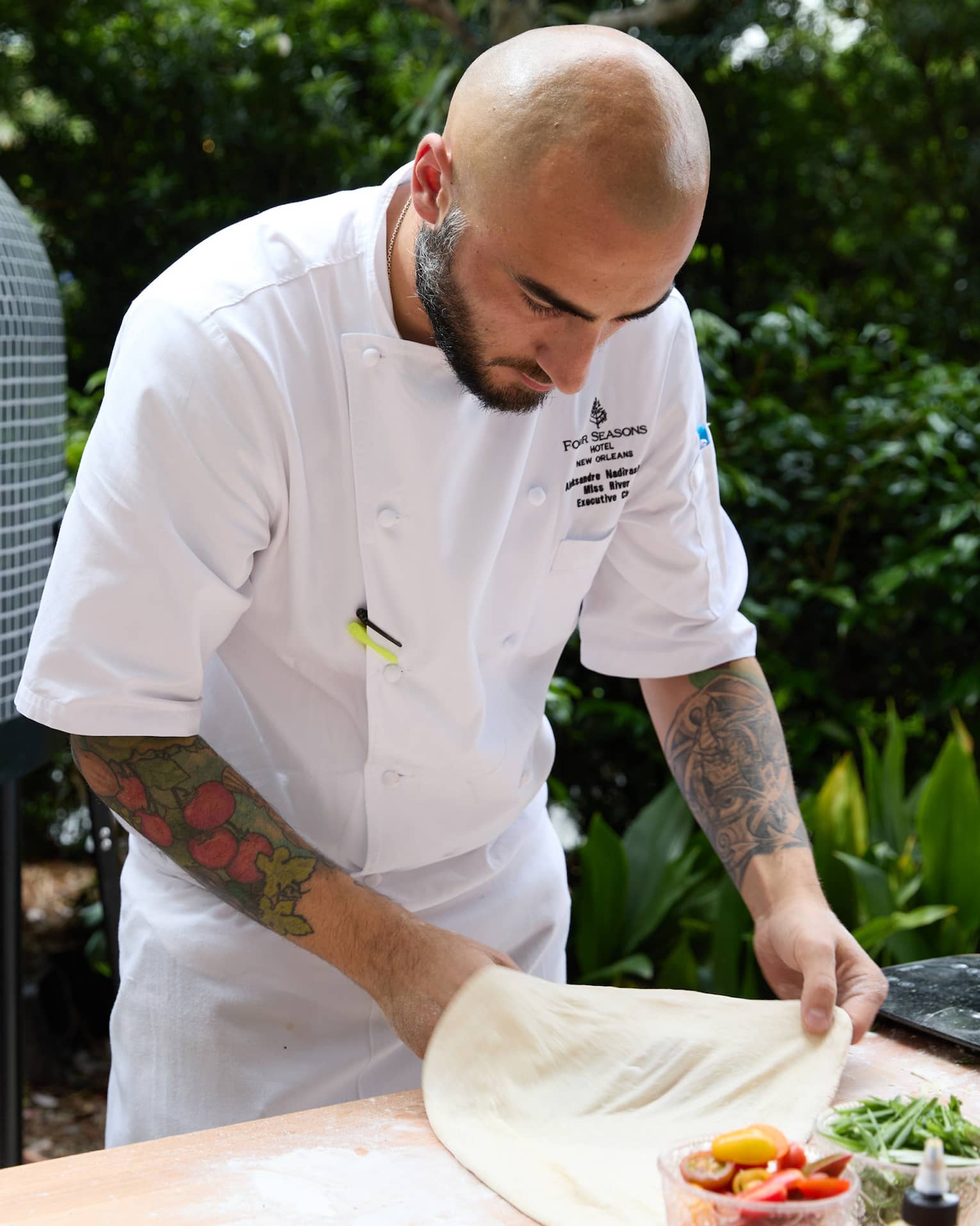 Person wearing a chefs coat and making food while outside.