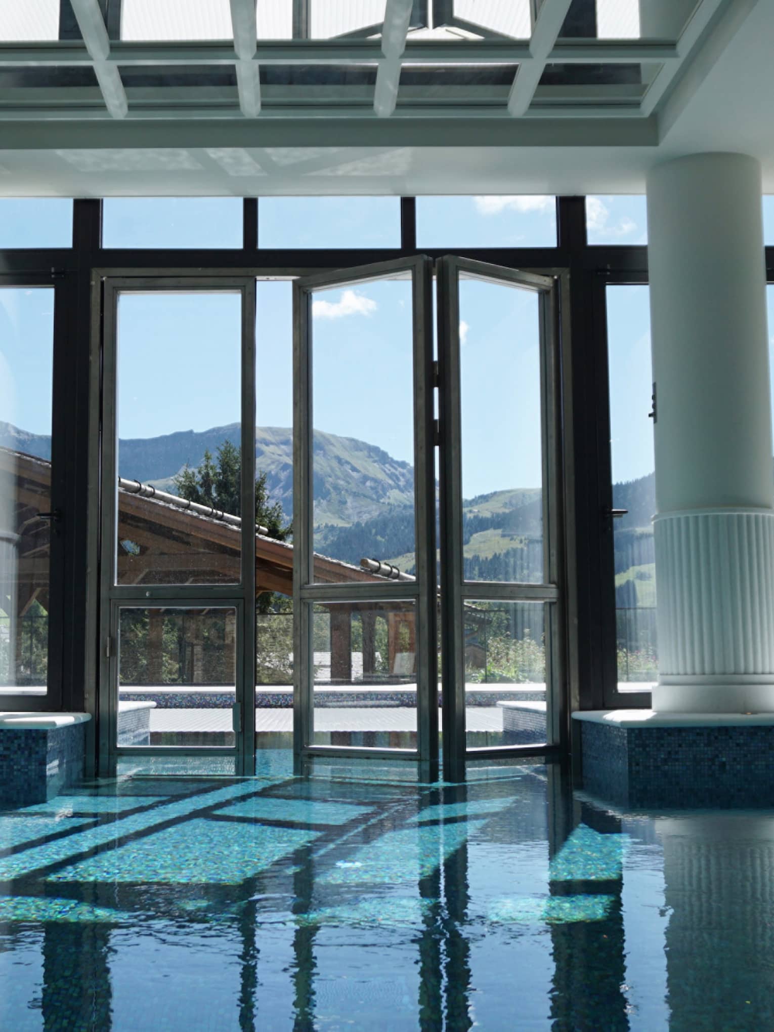 Large white pillars, beams, skylights over indoor swimming pool