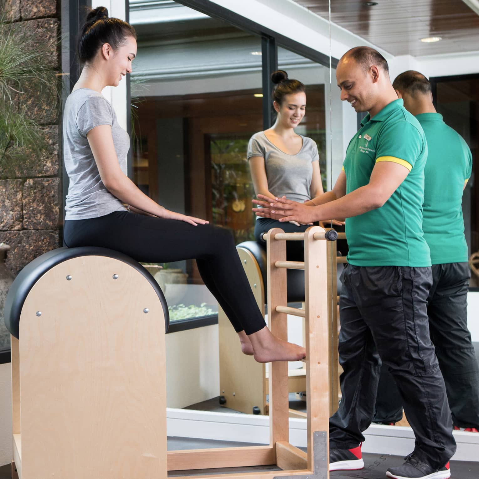Four Seasons trainer assists woman balancing on pilates beam in Fitness Centre