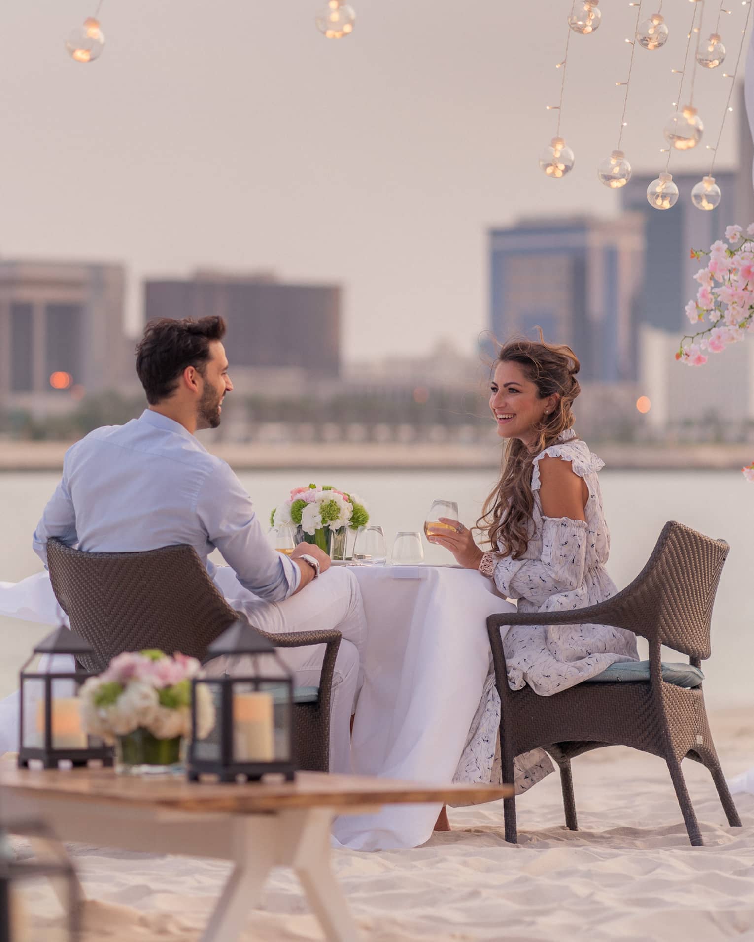 A man and woman enjoy a romantic dinner outside by the water overlooking the city