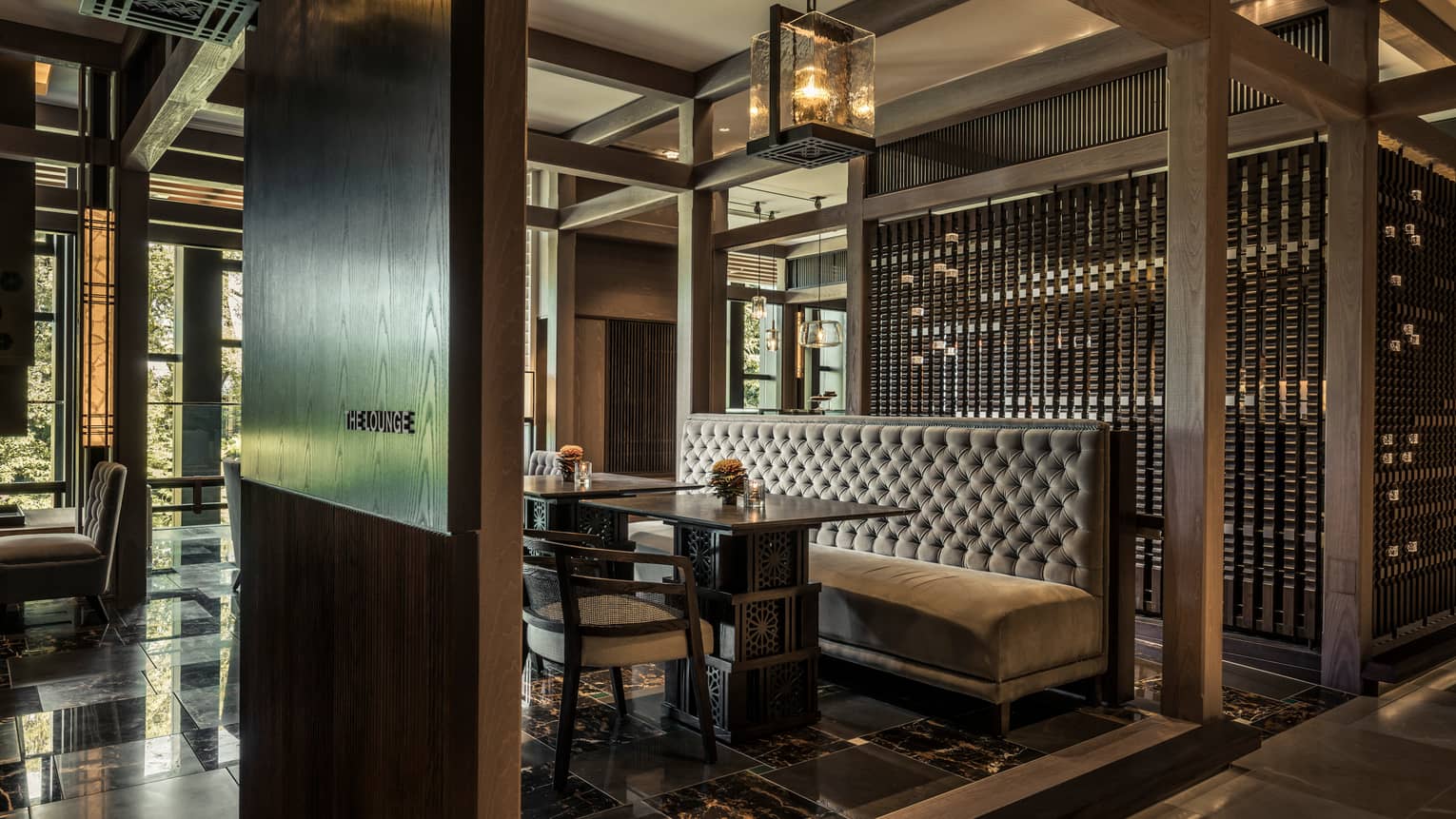 The Lounge plush velvet booth between dark wood walls under thick glass chandelier