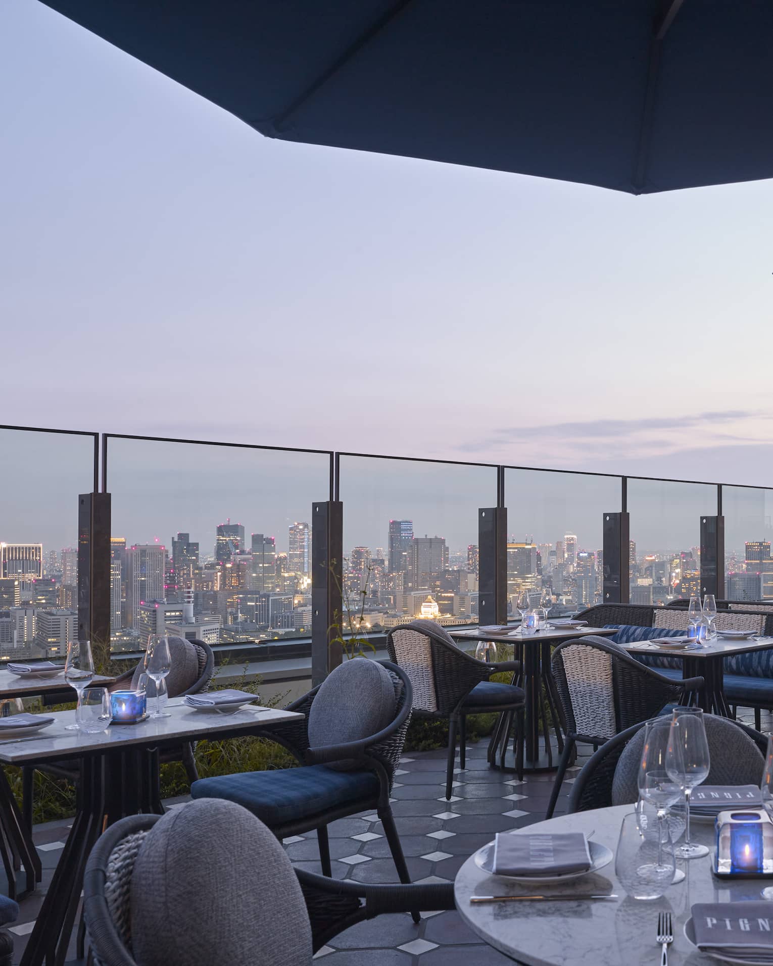 Pigneto Terraza rooftop patio dining tables at dusk, city view below