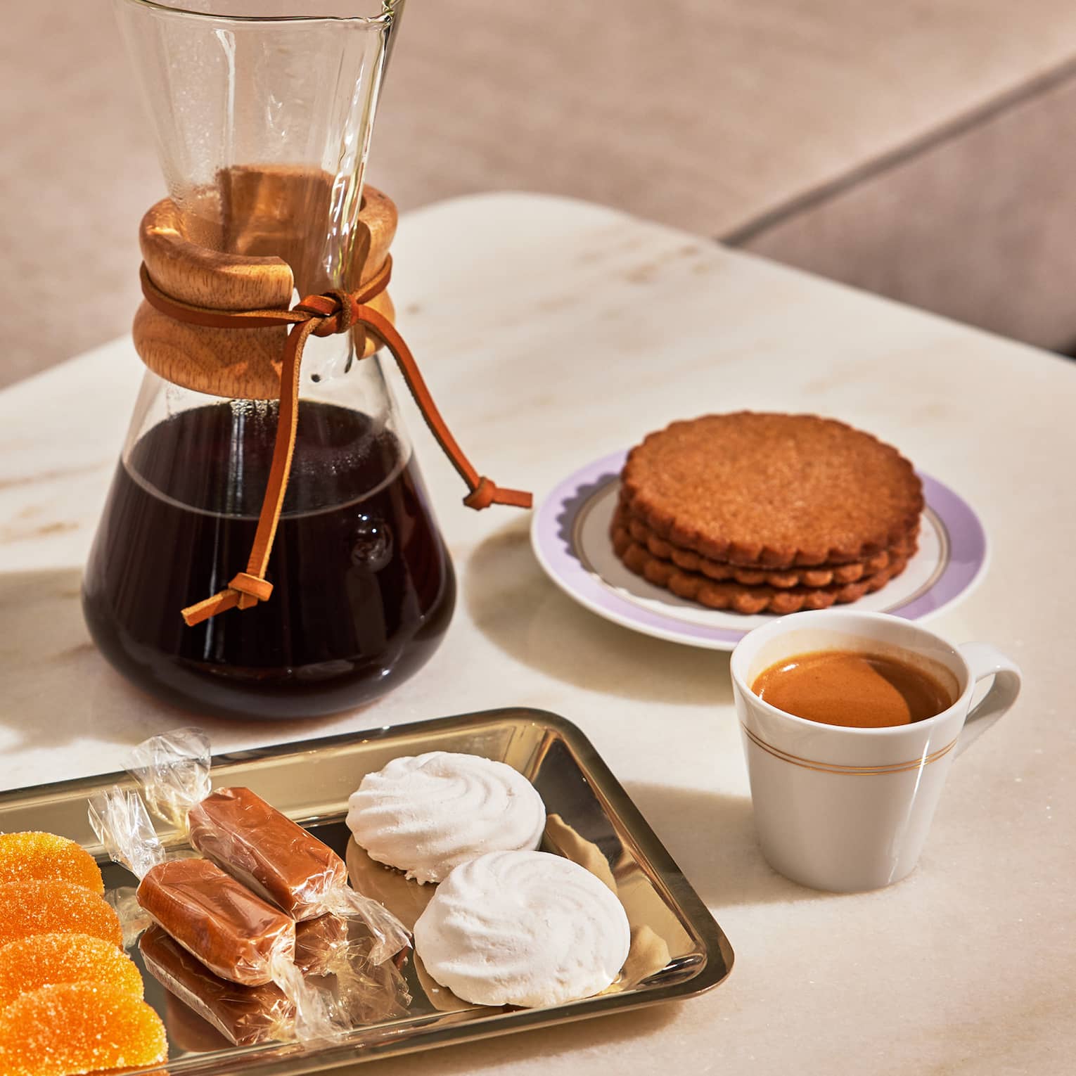 A glass carafe of coffee and plate of sweets, including meringue and Biscoff cookies
