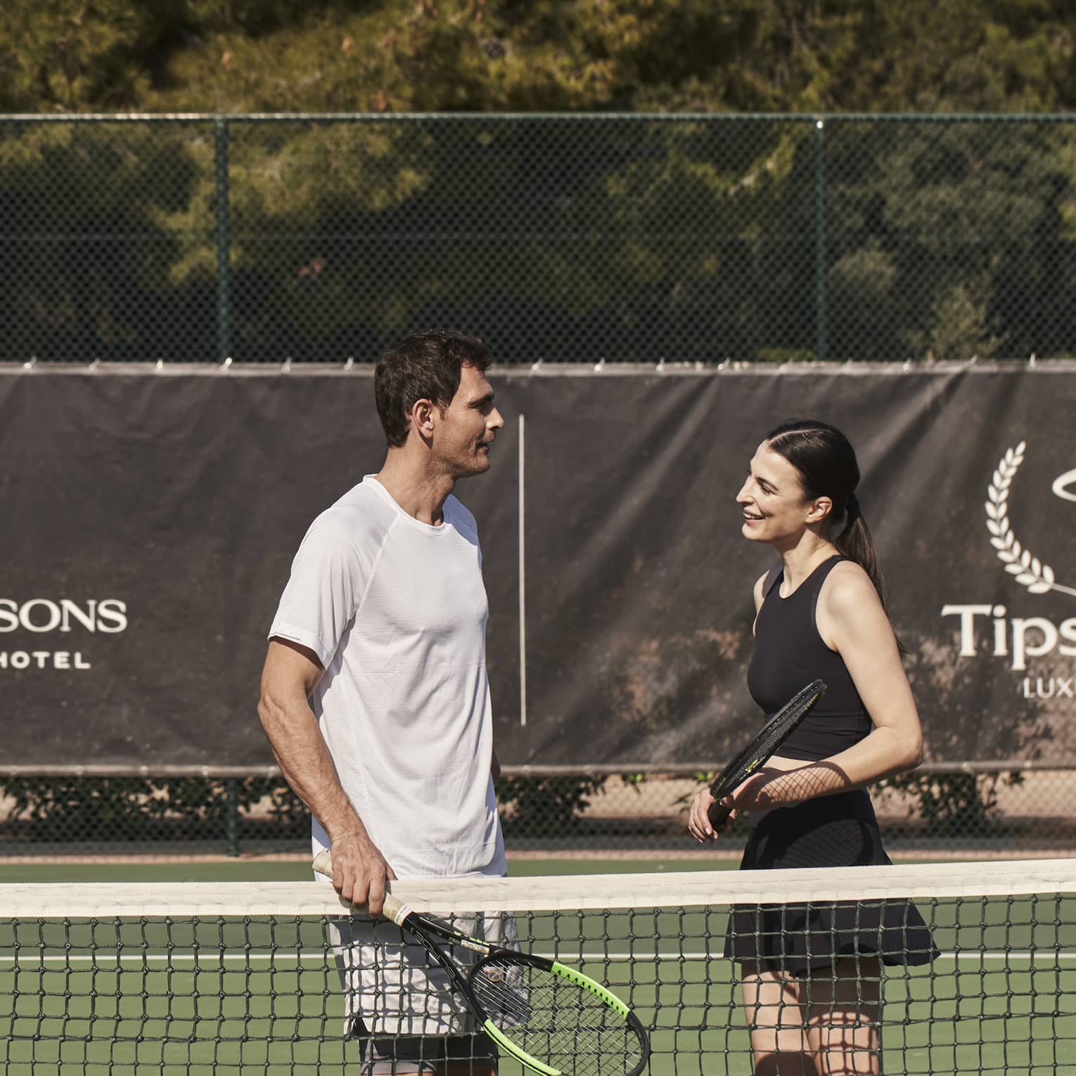 A man and woman holding tennis rackets on a court.