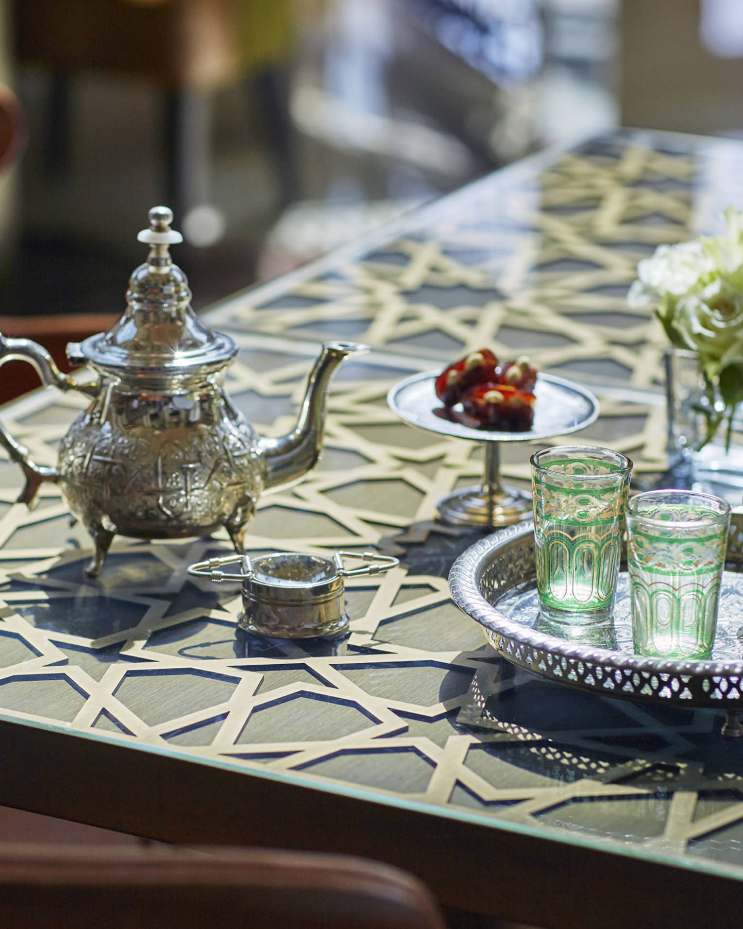 Small Moroccan-style tea pot and colourful glasses on silver tray on table