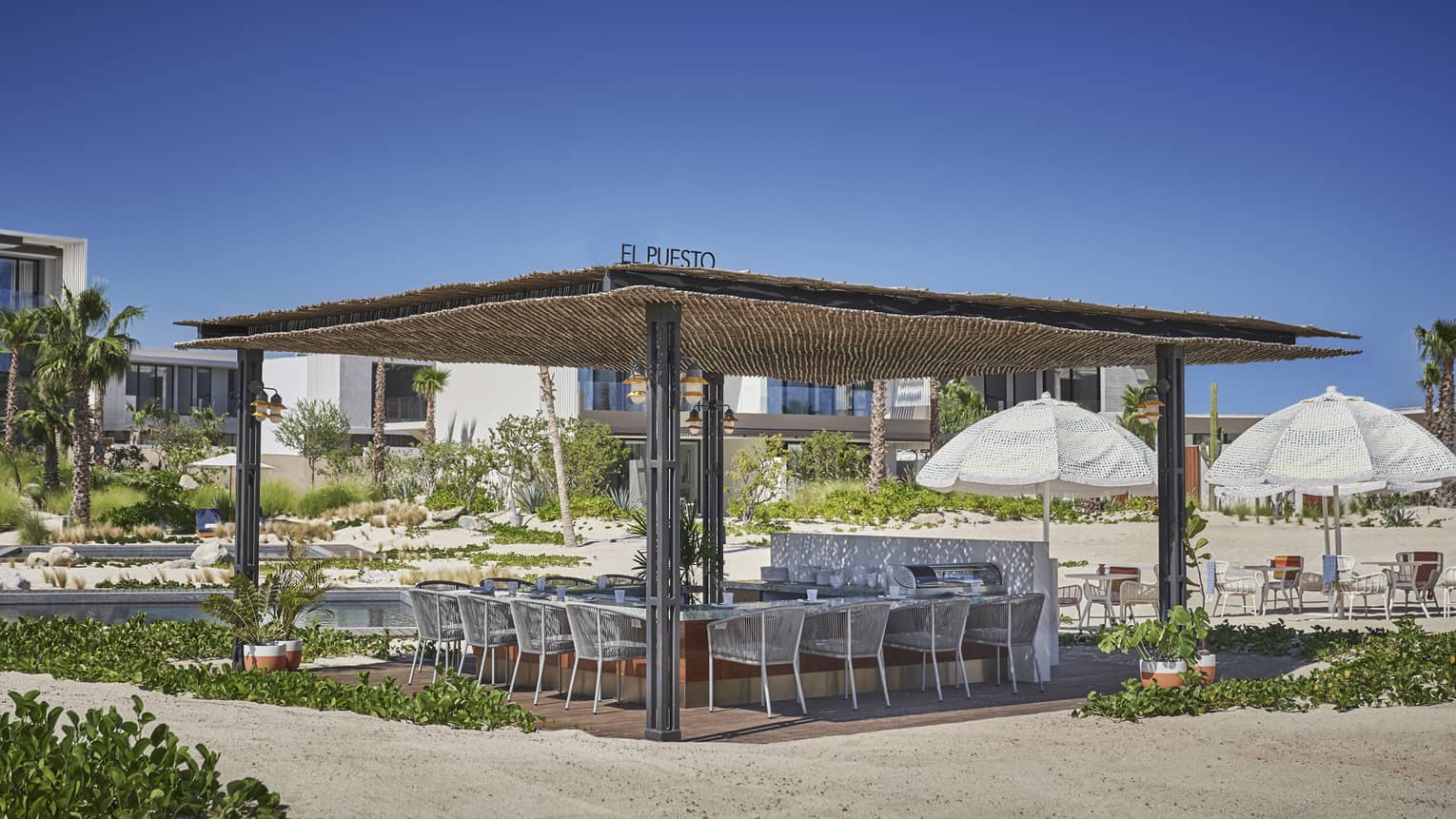 An outdoor kitchen with a wood covering, chairs surround a cooking station.