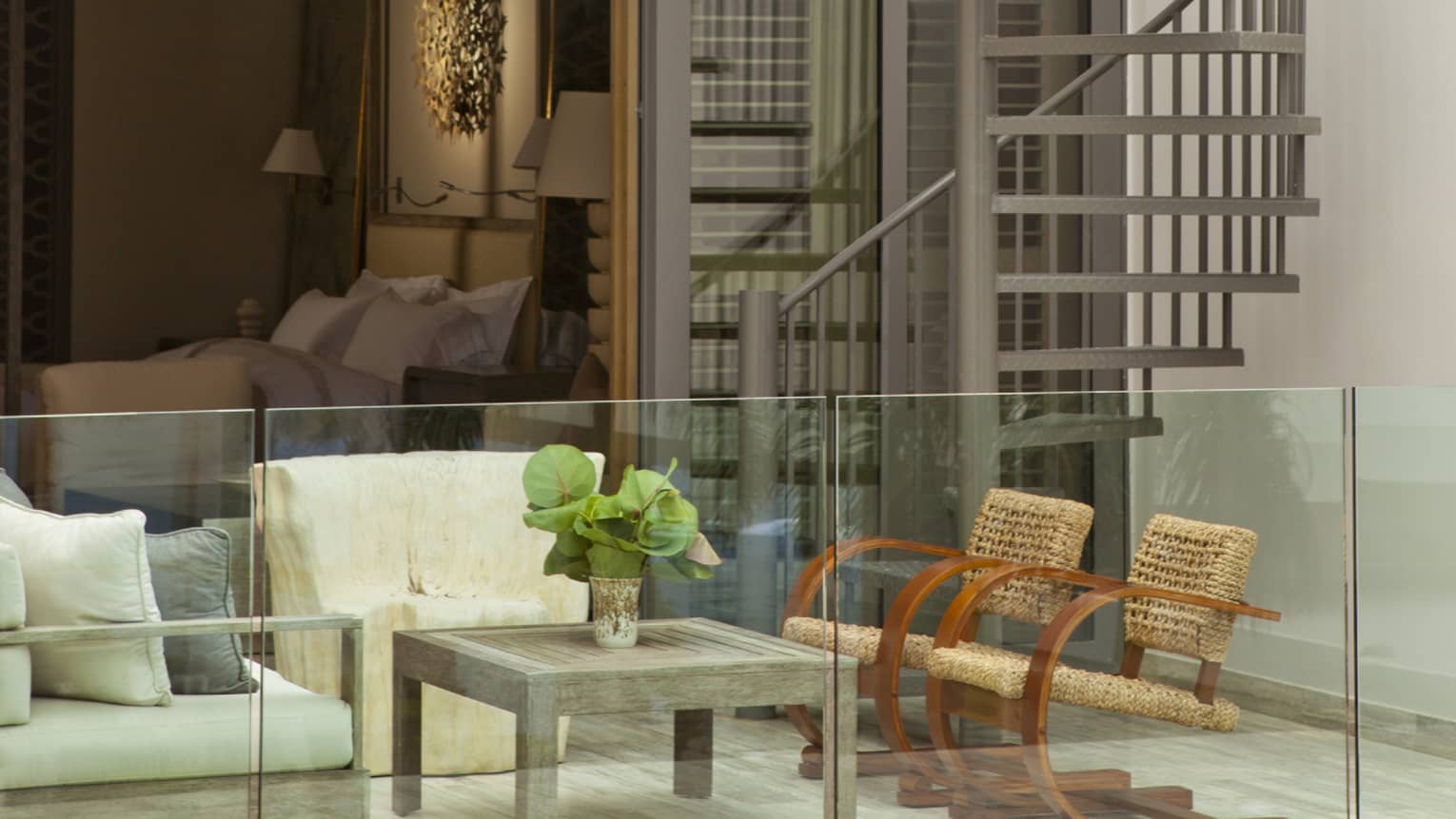 Private villa patio seating area behind glass balcony, bedroom in background, spiral outdoor staircase