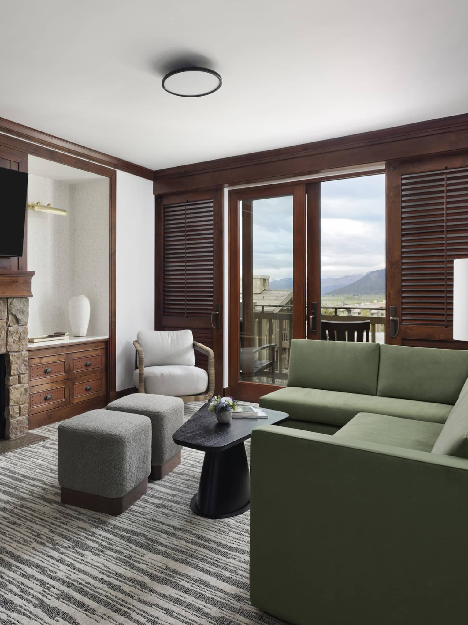 Spacious living area with rustic features like a stone fireplace and balcony with mountain views.