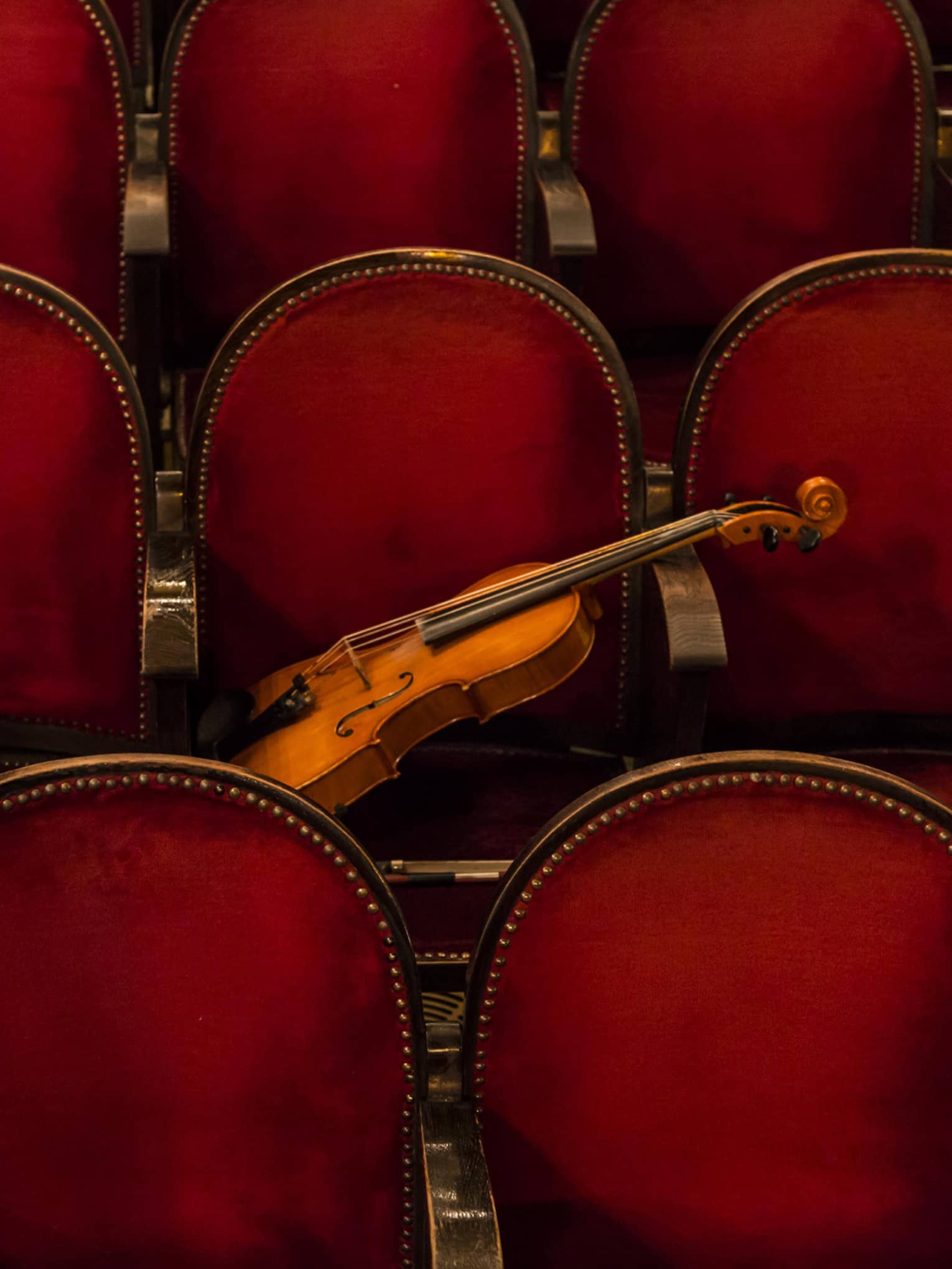 Red theatre chairs with a violin resting on one.