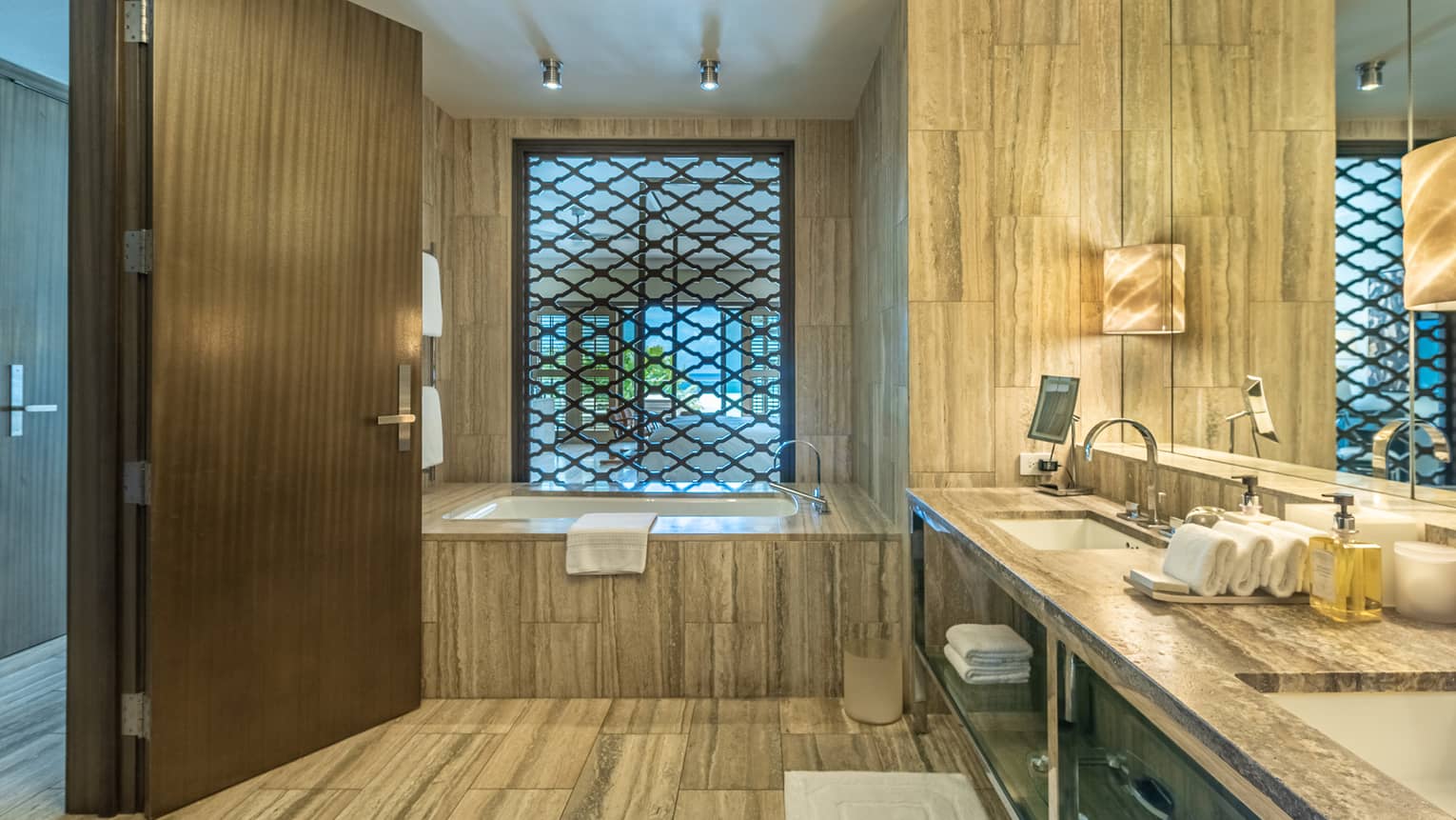 Rooftop Suite bathroom with large soaking tub, woodgrain floors and walls, vanity with double sink and intimate lighting