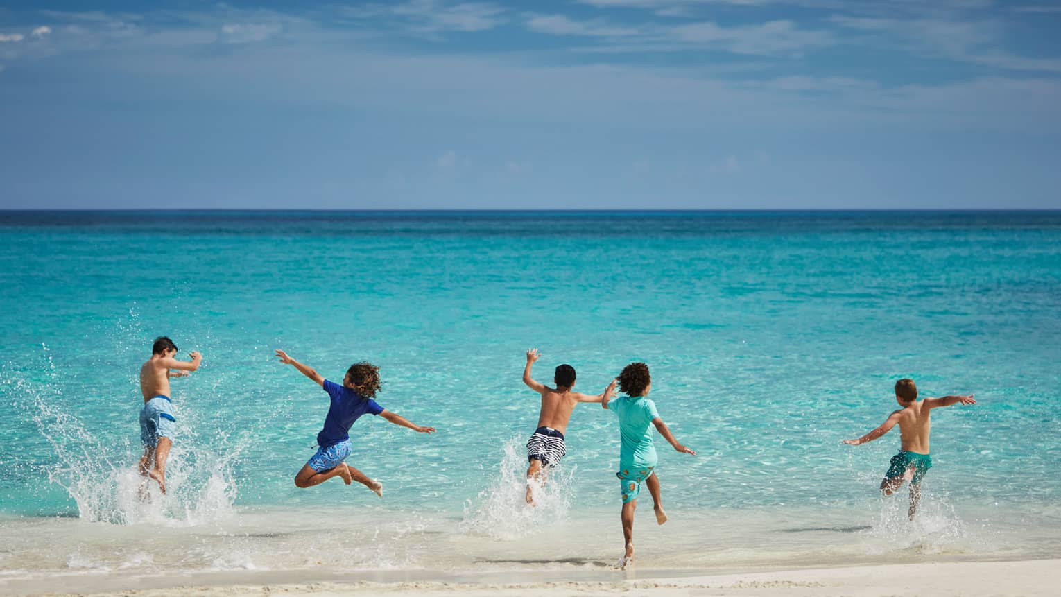 Children running into water from a beach.