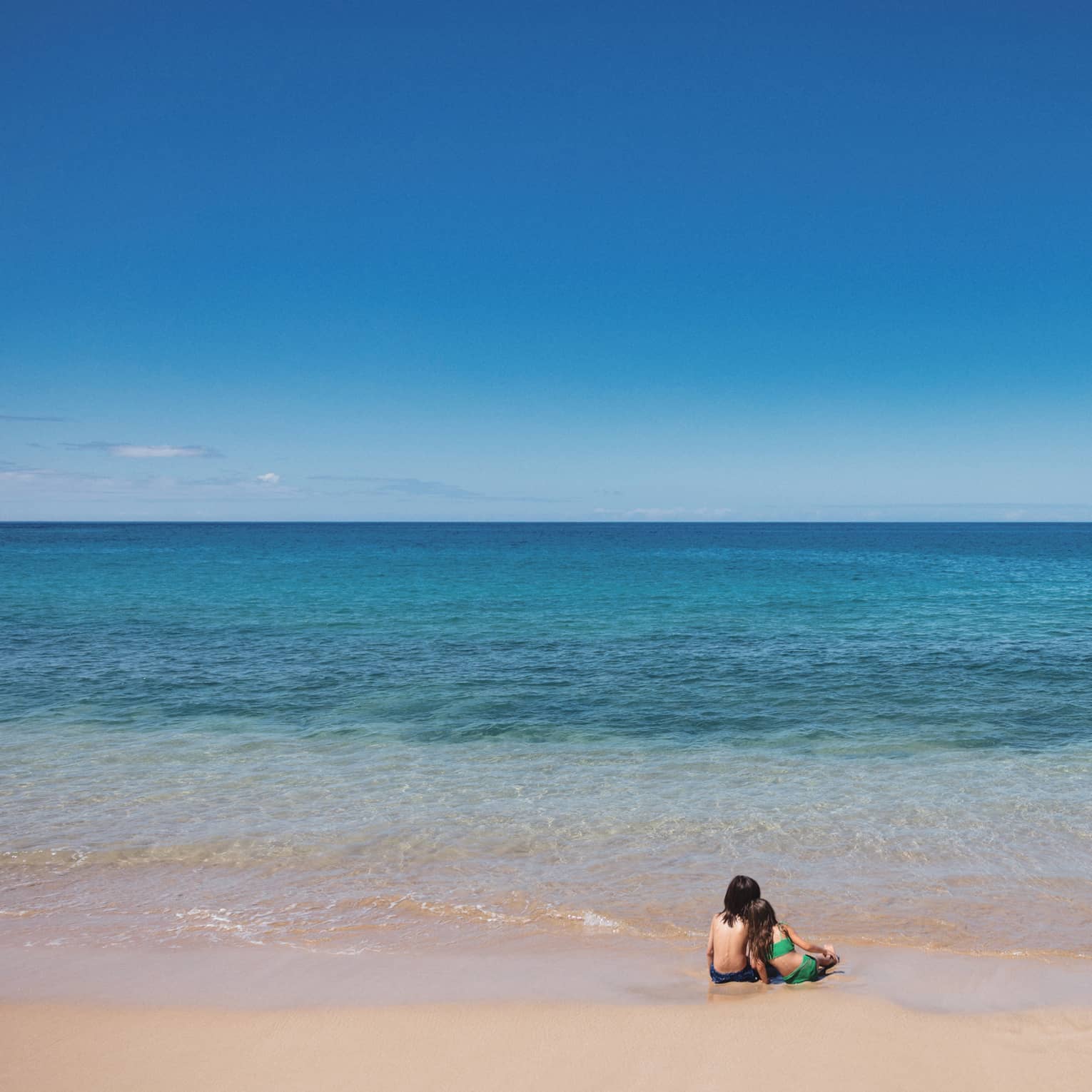 Children on beach with blue water in front of them