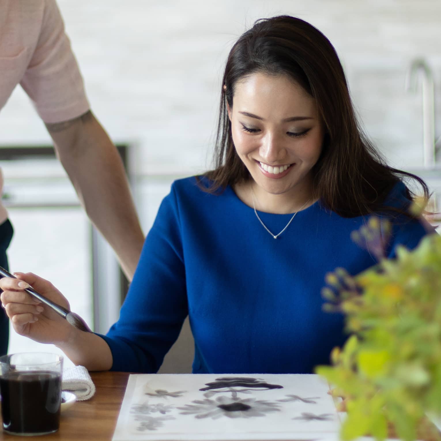 Person smiling while painting with watercolours at a table