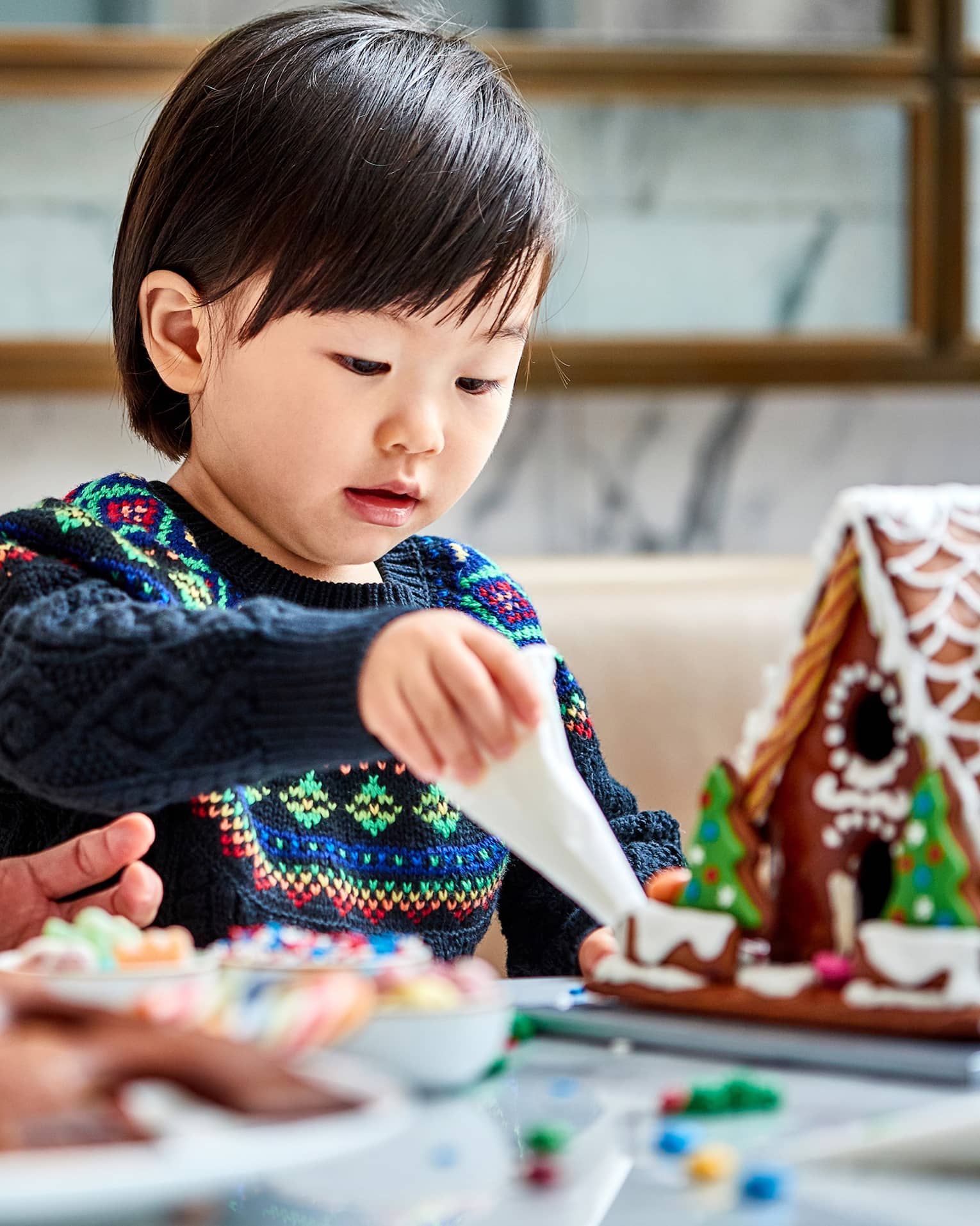 A mother and child make gingerbread houses together