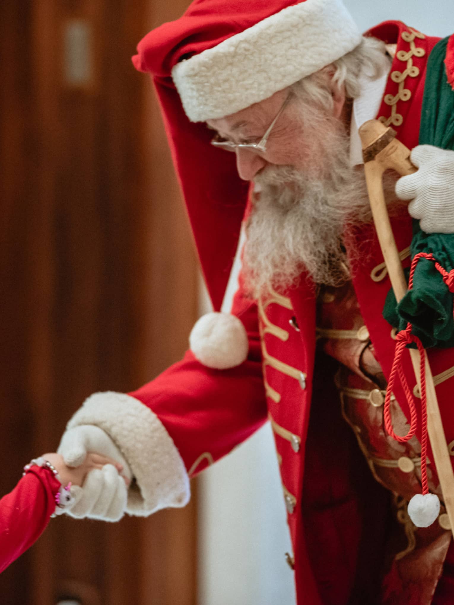 A man dressed as Santa Claus shakes little girl's hand
