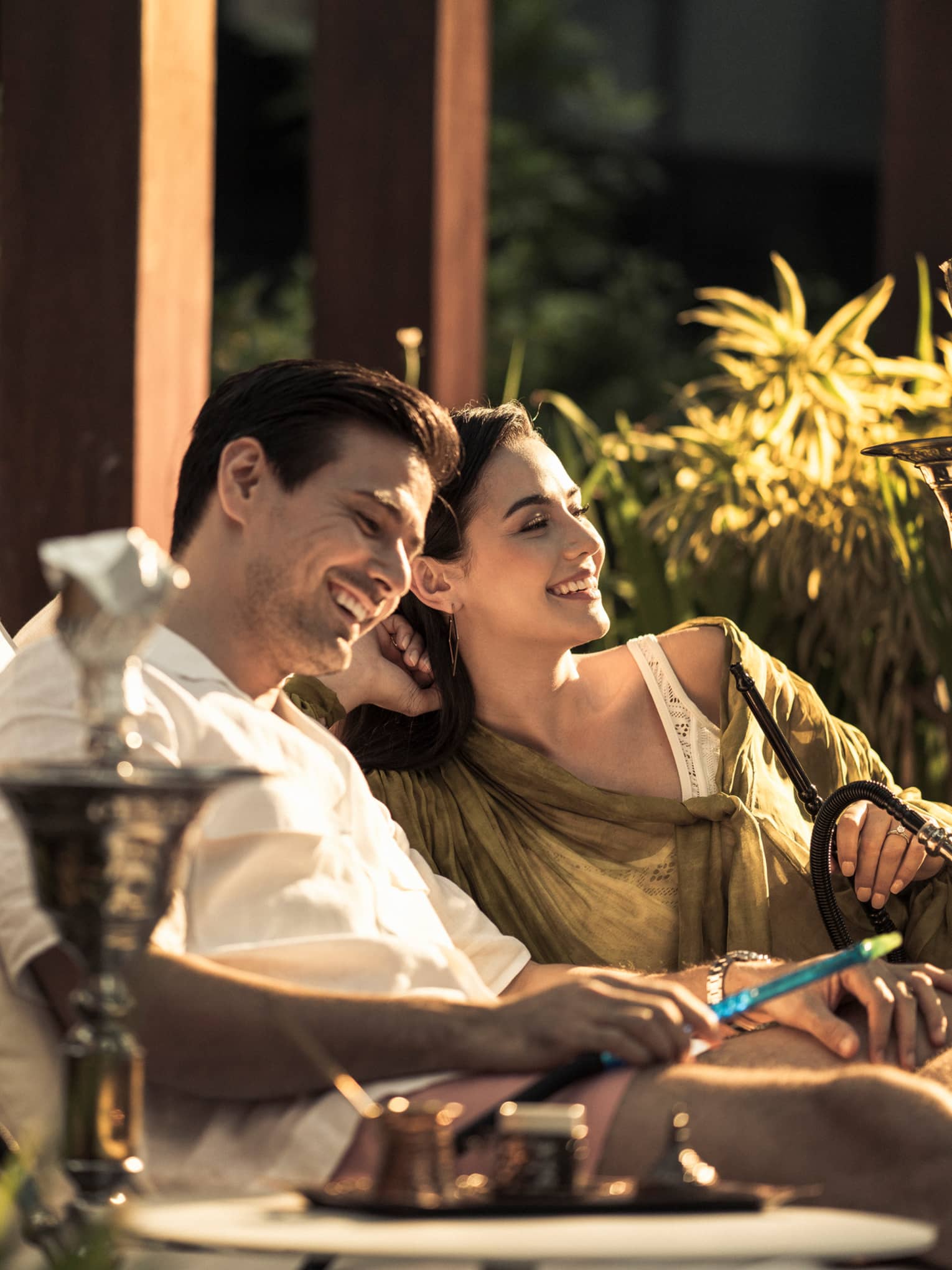 A couple sits together on lounge chairs outside at Four Seasons Hotel Kuala Lumpur